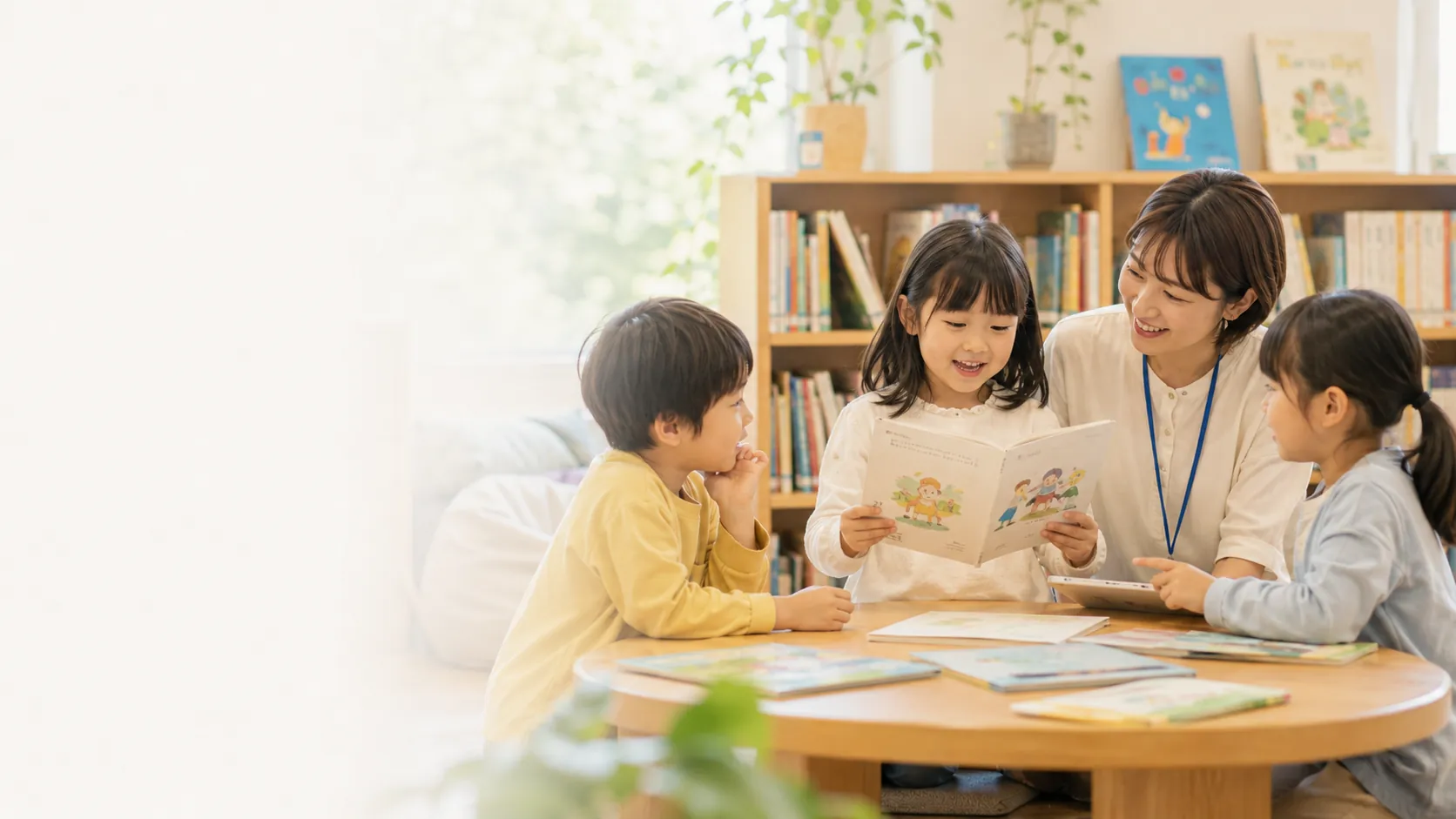 先生と子どもたちが図書館の読書コーナーで作品を読み合う様子