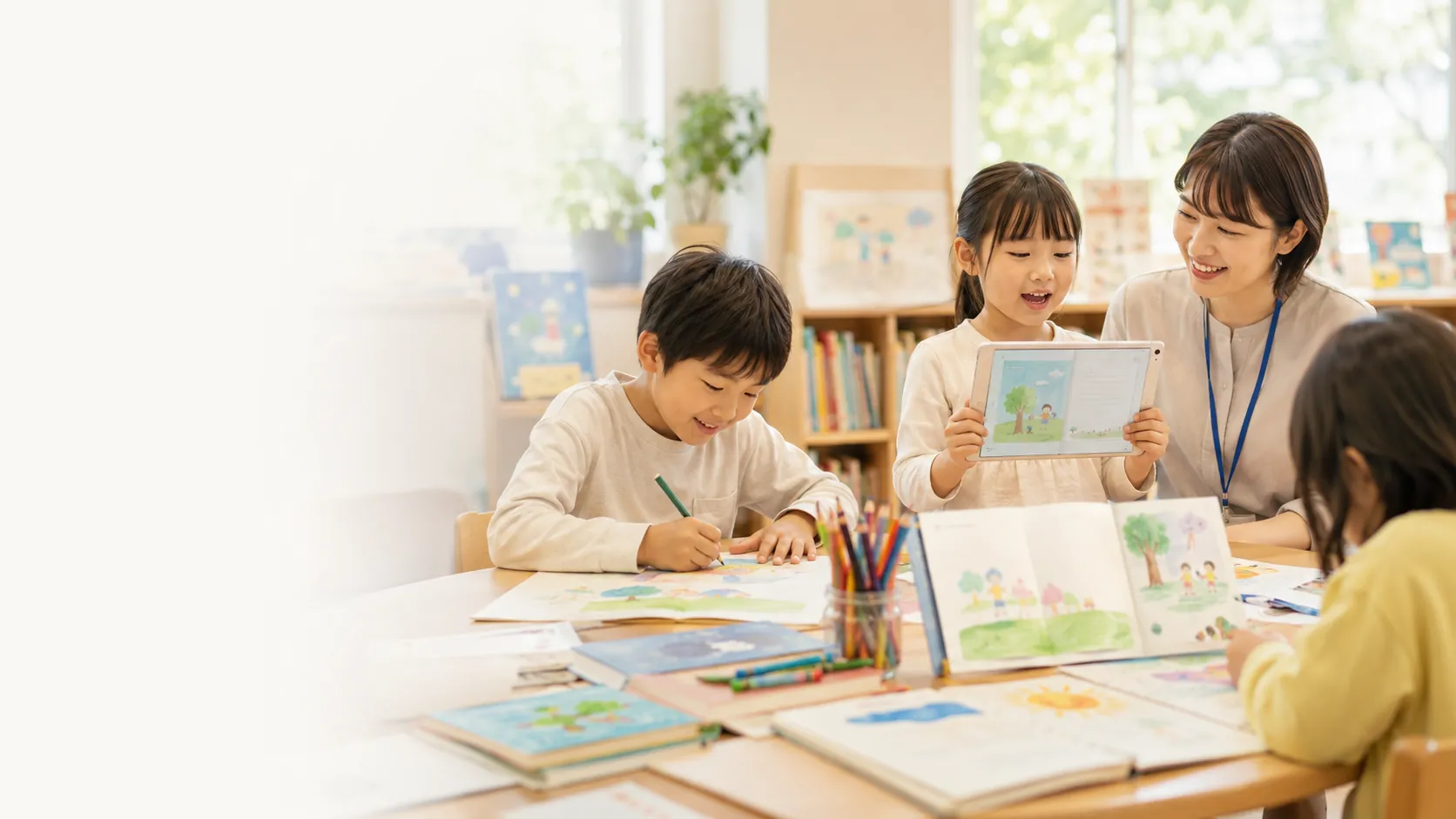 子どもたちが教室で絵を描き、タブレットで作品を見せている様子